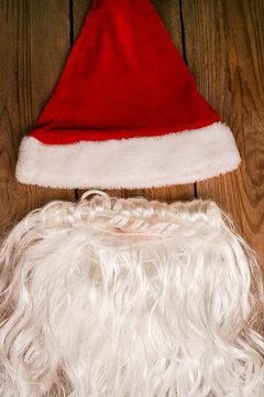Santa hat and beard on a wooden background. Symbolism of New Year's holidays. Christmas and new year concept. Change of clothes, change of image.