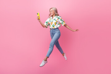 Full body photo of running fast model blonde wavy hair bring phone cant stop using her new iphone jumping isolated on pink color background - obrazy, fototapety, plakaty