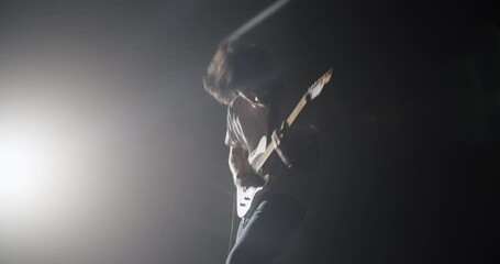 Professional male guitarist performing energetic song on guitar