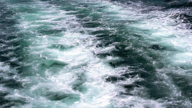 Spray, waves, water splashes and turbulent current behind the engines of a large motorboat in the sea