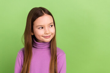 Fototapeta premium Portrait of cute schoolgirl with long hairstyle dressed violet sweatshirt look at discount empty space isolated on green color background