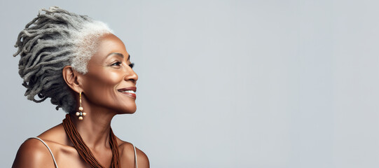 Banner Beautiful elegant mature grey haired middle aged african American woman with perfect skin and smile , with dreadlocks on head on grey background, copyspace for text.