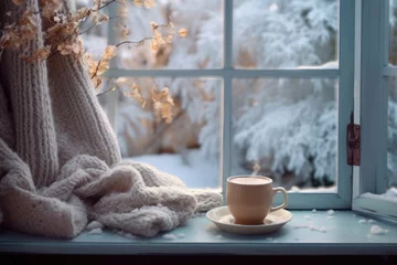 Fotobehang Cup of coffee on the windowsill in cozy room, winter scene outside the window © Lana_M