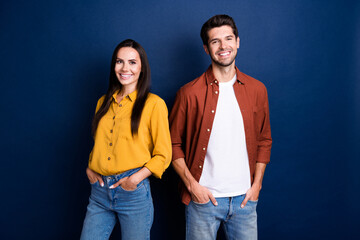 Photo of two cheerful corporate people toothy smile put hands pockets posing isolated on dark blue color background