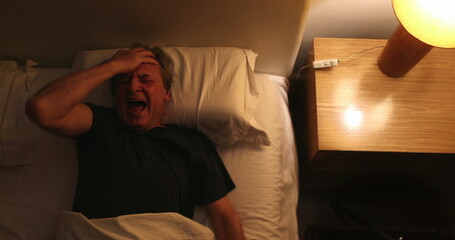 Person waking up at night, turning bedside light ON, man stretching and getting up from bed