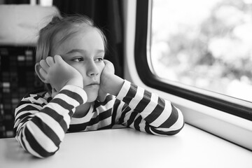 Little boy is traveling on the train. Kid travels on a train. Cute child looking out the train window.