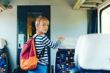 Schoolboy leaving wagon. Cute preteen boy getting off train. Little passenger standing inside train.