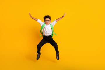 Fototapeta na wymiar Full size portrait of excited energetic small boy jumping carry rucksack empty space ad isolated on yellow color background