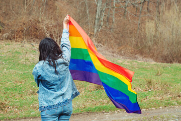 Celebrating the lgbt lesbian women rights. Woman holding the rainbow flag on the nature.