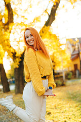 Happy woman walking in autumn park. Autumn fashion, lifestyle and holidays. Redhead woman.