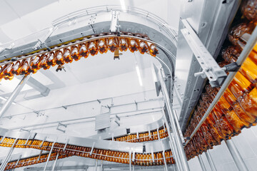 Concept modern production line of brewery industry. Conveyor with brown plastic beer bottles with...