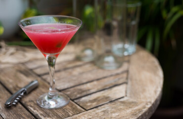 Red cocktail with ice in a glass on a wooden table