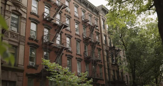 Establishing Shot with Old Renovated Brownstone House in New York City. Urban Architecture During Day Time of a Brick Multi-Storey Apartment Building with Emergency Stairs and Air Conditioning