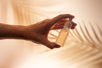 Cosmetic serum with dropper in woman hand beige palm live shadow background