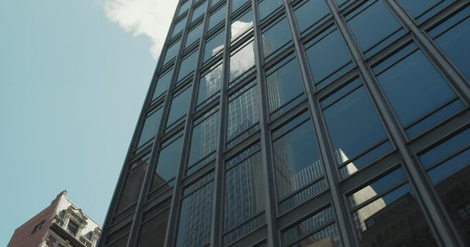 Low Angle Footage of a Business Skyscraper Reflecting From a Modern Glass Building. Cinematic Footage of Urban Architecture of New York City From a Moving Car on a Clear Sunny Day