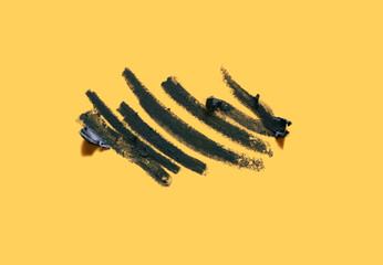 Fototapeta premium Cosmetic navy blue colored eye pencil strokes on mango orange background