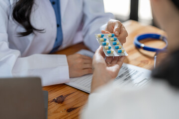 Obraz na płótnie Canvas doctor or pharmacist advises patients about pills. The doctor prescribes medication sitting at a table in the clinic office. to find the best course of treatment. follow-up treatment