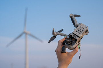 Woman holding a crashed drone against the backdrop of windmills. 