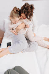 Bedtime Bliss: Playful Mother-Daughter Bonding in a Cozy Bed.