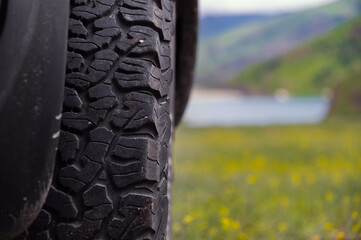 Transport, driving and car concept, close-up of a car wheel on green lush grass. A car wheel stands in the mountains in summer