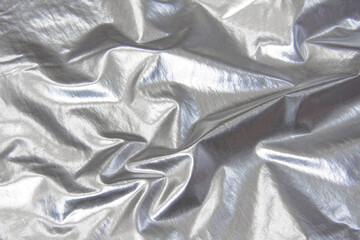 Wrinkled silver metallic fabric. Folded fabric which looks like foil. Metallic cloth. Light sliver...