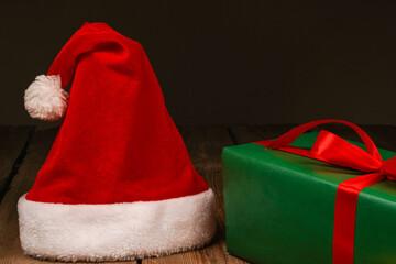 Top view photo of Christmas Flatlay gift box and Christmas tree decorations. Santa hat on a wooden backgroundon. Christmas background with place for text. Copyspace. Christmas tree toys.