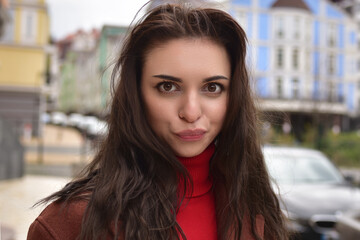 Portrait of a cute young woman in a brown autumn coat on the street with funny emotion