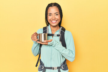 Indonesian hiker holding camping cup on yellow