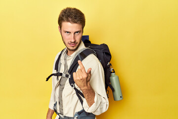 Traveler with mountain gear and yoga mat pointing with finger at you as if inviting come closer.