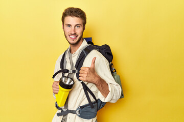 Fototapeta na wymiar Traveler with mountain backpack and torch smiling and raising thumb up