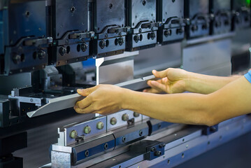 Close up the bending machine operator hold the sheet metal parts.