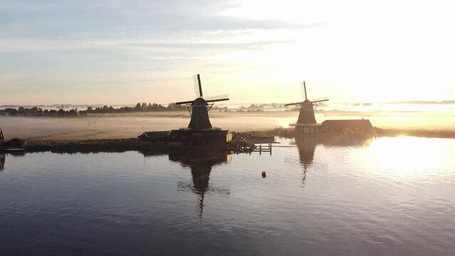 Ancient wooden windmills of Zaanse Schans during sunrise. The golden rays reveal the history of the Netherlands. 4k video