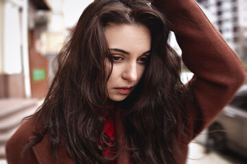 Portrait of an very upset woman in an autumn coat on the street touches her head. depression and frustrating concept