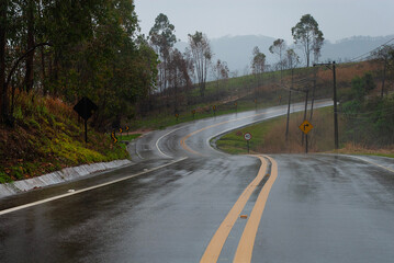 Paisagem de estrada molhada e sinuosa com árvores nas margens em dia chuvoso 
