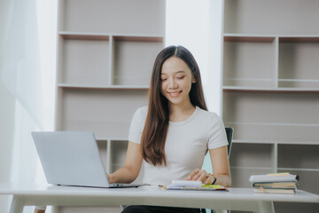 Happy Asian businesswoman paying online using mobile phone and laptop at office