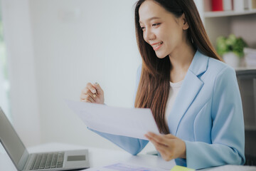 Happy Asian businesswoman working in modern office using laptop computer