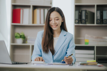 Happy Asian businesswoman working in modern office using laptop computer