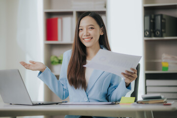 Happy Asian businesswoman working in modern office using laptop computer