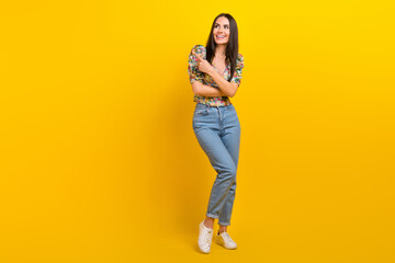 Fototapeta premium Full size photo of gorgeous woman wear stylish top denim pants look directing at promo empty space isolated on yellow color background