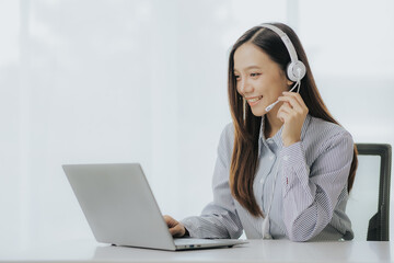 Portrait of Asian female call center operator with headset working support hotline in modern office...