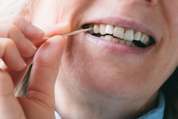 A woman cleans her dirty teeth with a wooden toothpick from food. Oral health and hygiene
