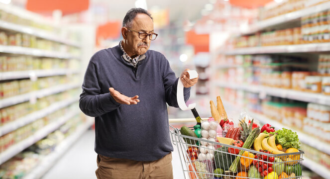 ature man in a supermarket holding a bill