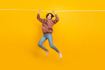 Full body photo of energetic overjoyed lady arms hold hanging rope isolated on yellow color background © deagreez
