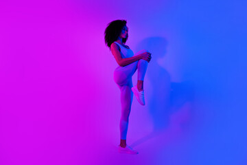 Full body profile portrait of slender sporty lady hands hold stretching leg isolated on colorful neon background