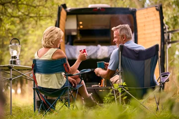 Foto op Plexiglas Rear View Of Senior Couple Camping In Countryside With RV Drinking Coffee By Outdoor Fire © Monkey Business