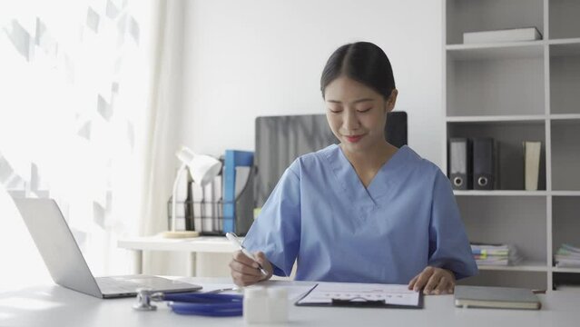 Young Asian nurse working on patient documents at her desk alone in the hospital