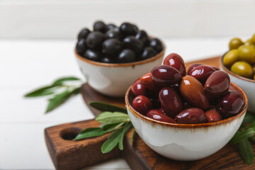 Green and black olives on a textured background. Different types of olives in bowls and olive oil with fresh olive leaves. Delicacy.Mediterranean Kitchen. Copy space.