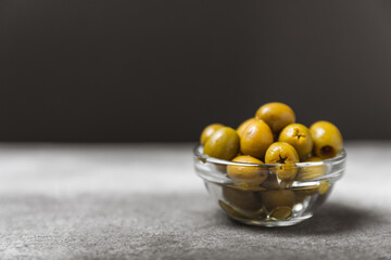 Green and black olives on a textured background. Different types of olives in bowls and olive oil with fresh olive leaves. Delicacy.Mediterranean Kitchen. Copy space.