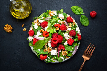 Gourmet salad with fresh raspberries, soft goat cheese, red onion, nuts, spinach and mixed herbs,...