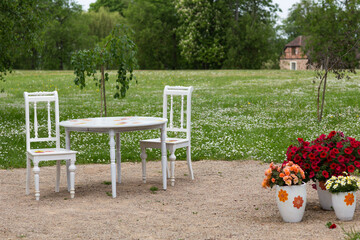 a white table and two vintage chairs stand in the park for a wedding ceremony 